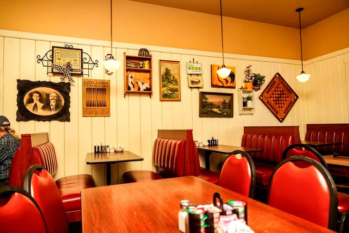 The warm, welcoming dining room at Cook's Kitchen — red booths, local art, and a community feel